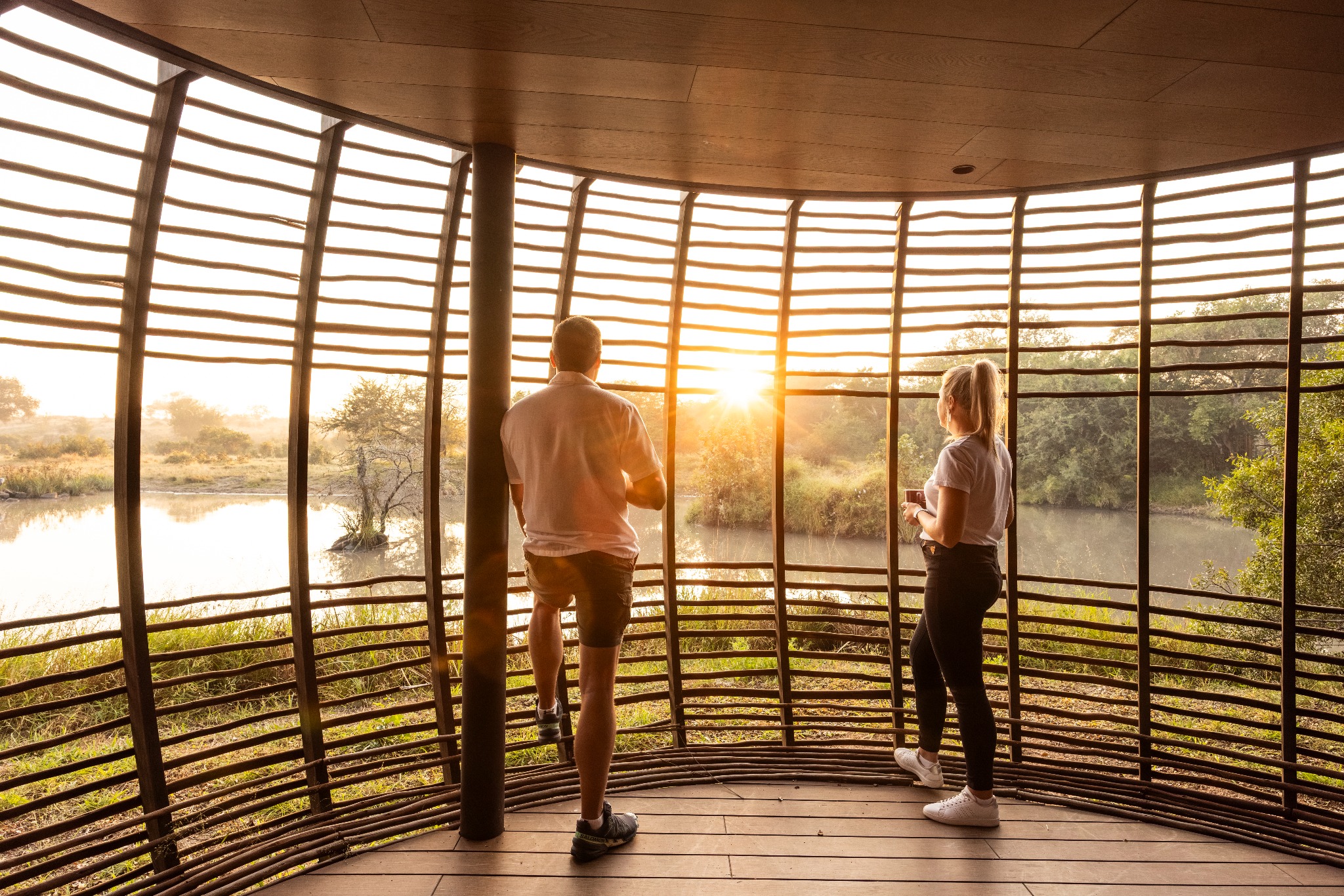 Guests enjoying the sunrise through the curved timber screens at Tanda Tula