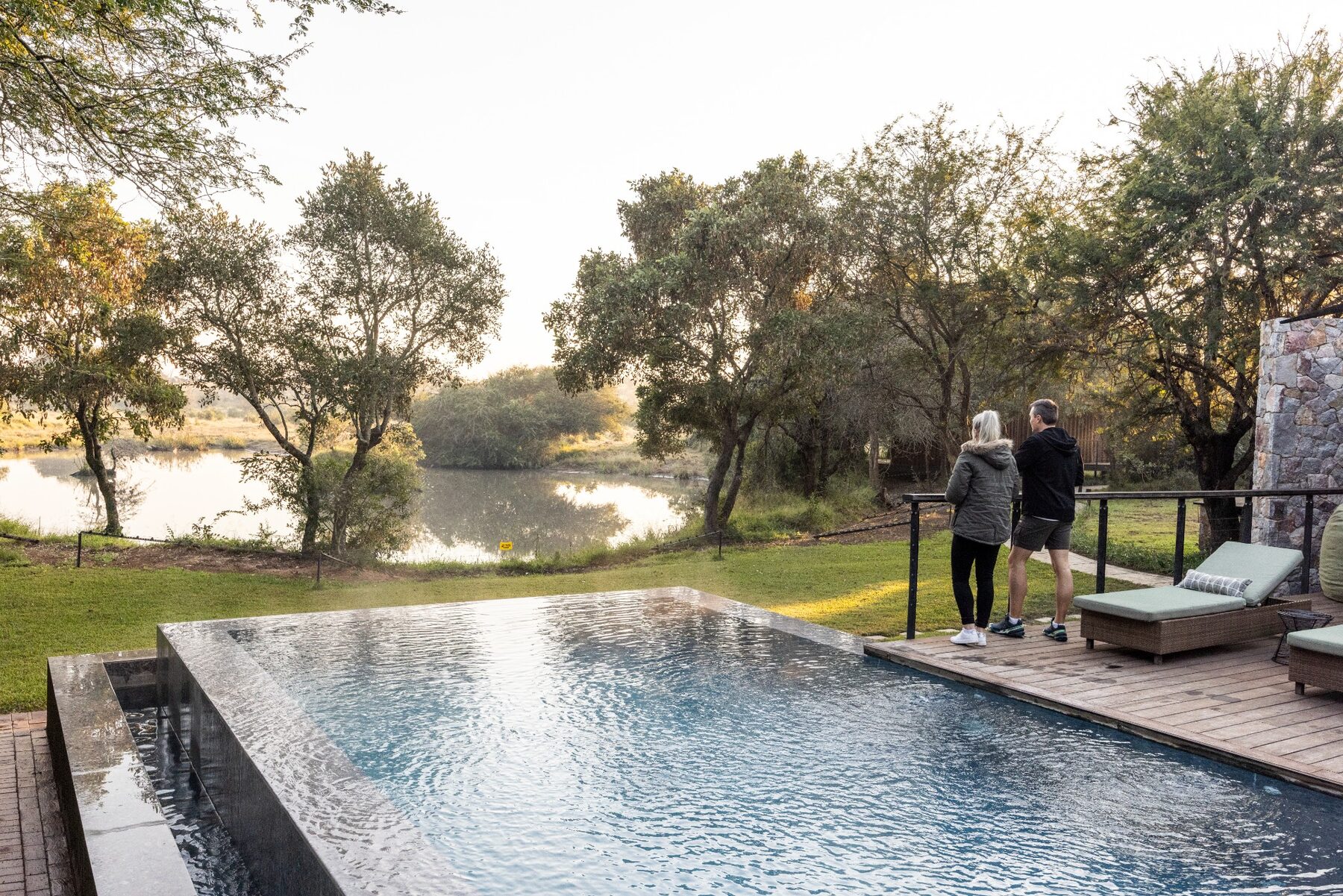 Guests overlooking a waterhole and pool in the African bushveld